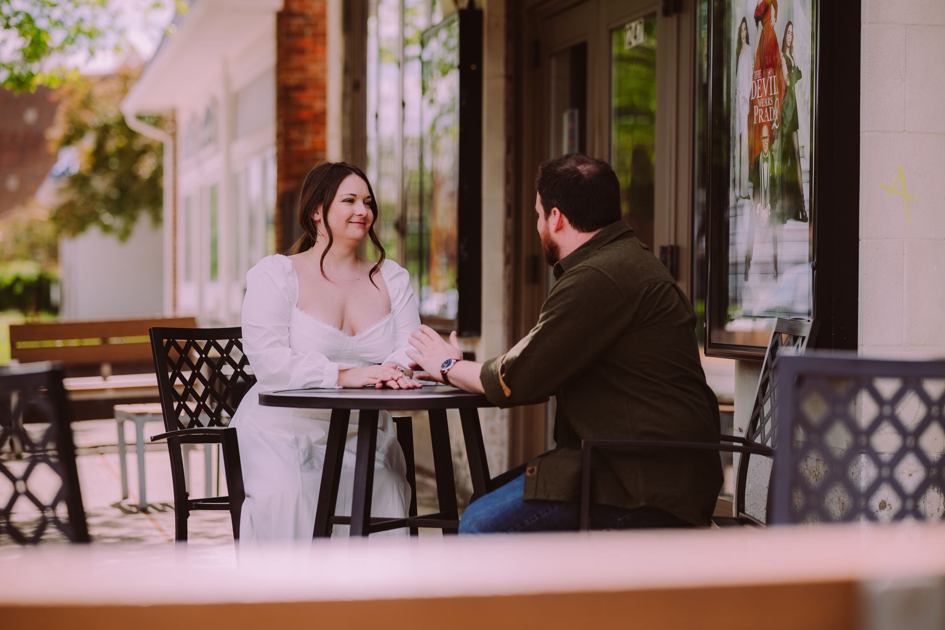 Two people chatting at an outdoor café table on a sunny patio