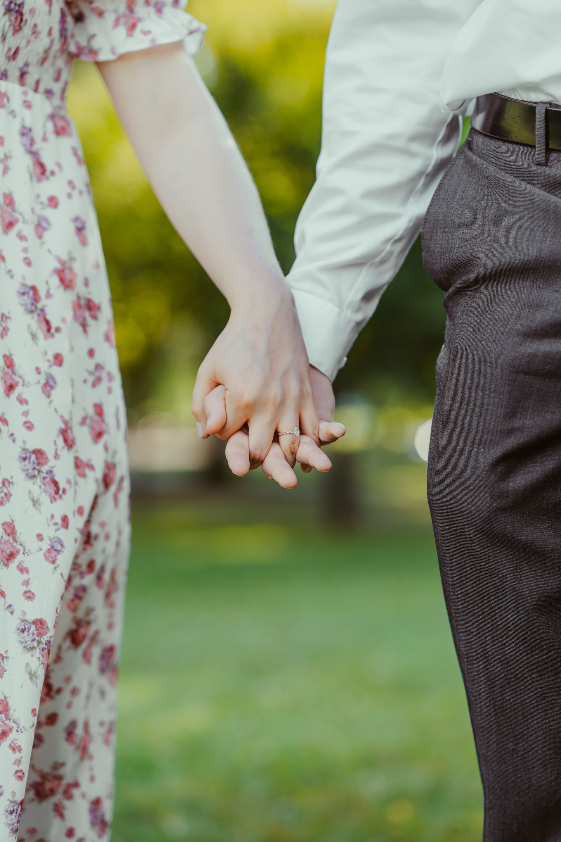 A man and a woman are holding hands in a park.