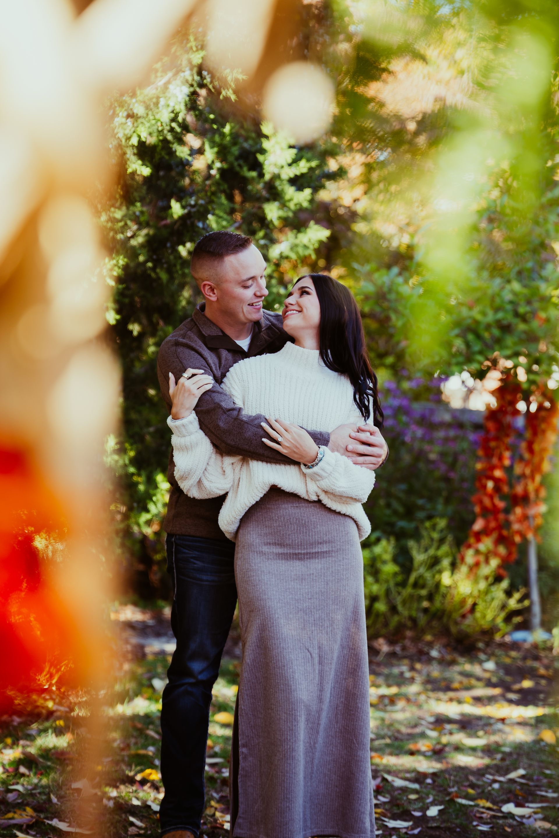 Couple embracing in a garden, smiling at each other. 