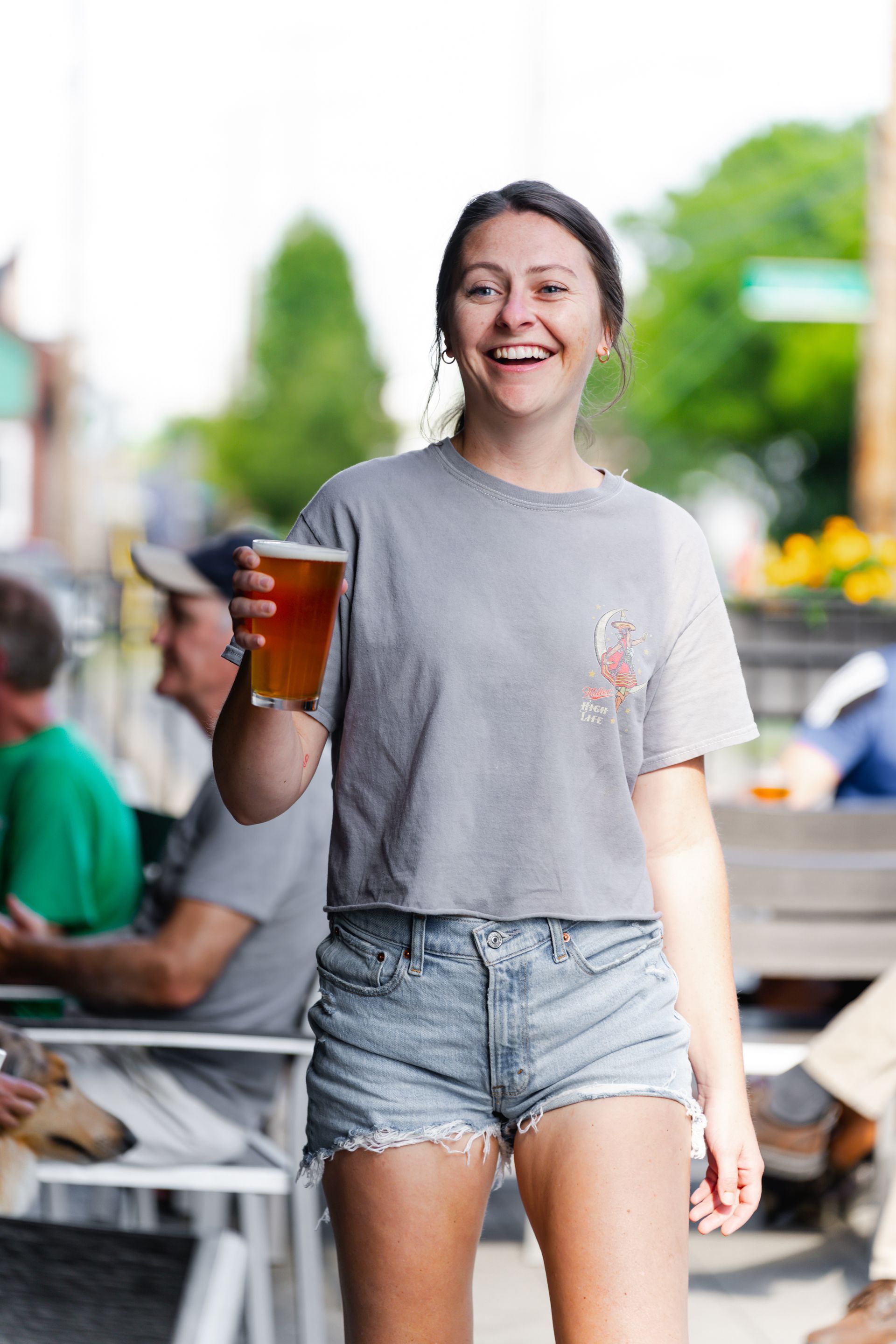 A woman is holding a glass of beer and smiling.