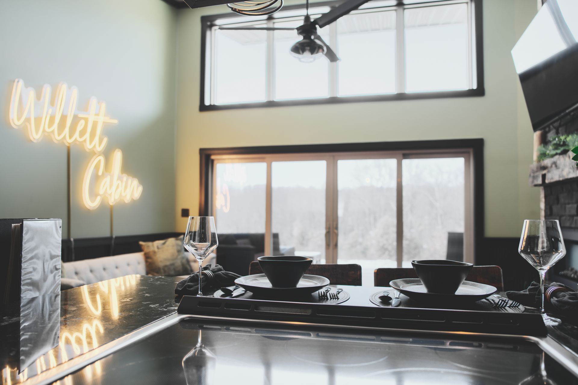 Modern kitchen with black counters, large window, and glowing wall sign reading “Willit Club”