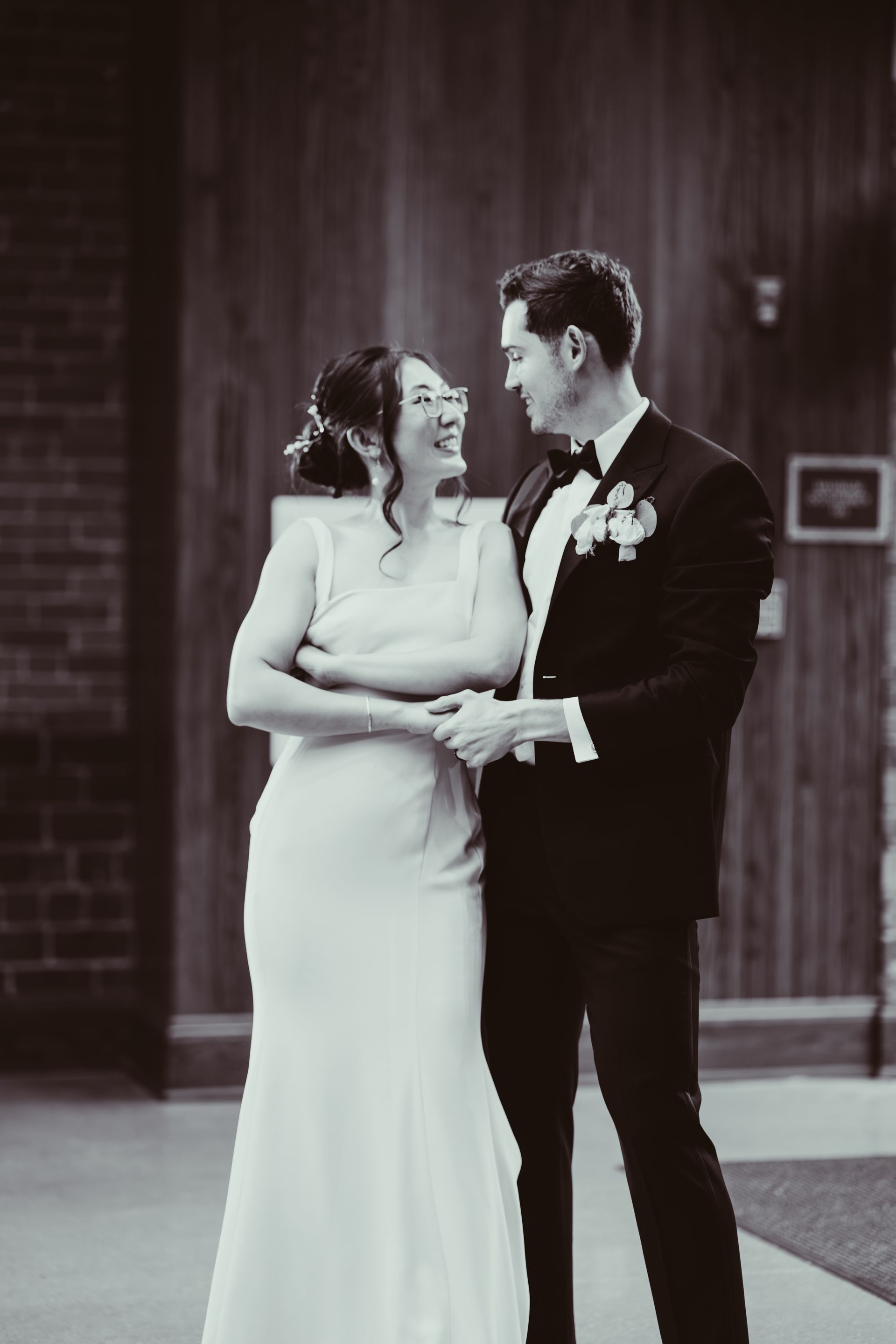 Bride and groom smiling at each other in front of a building