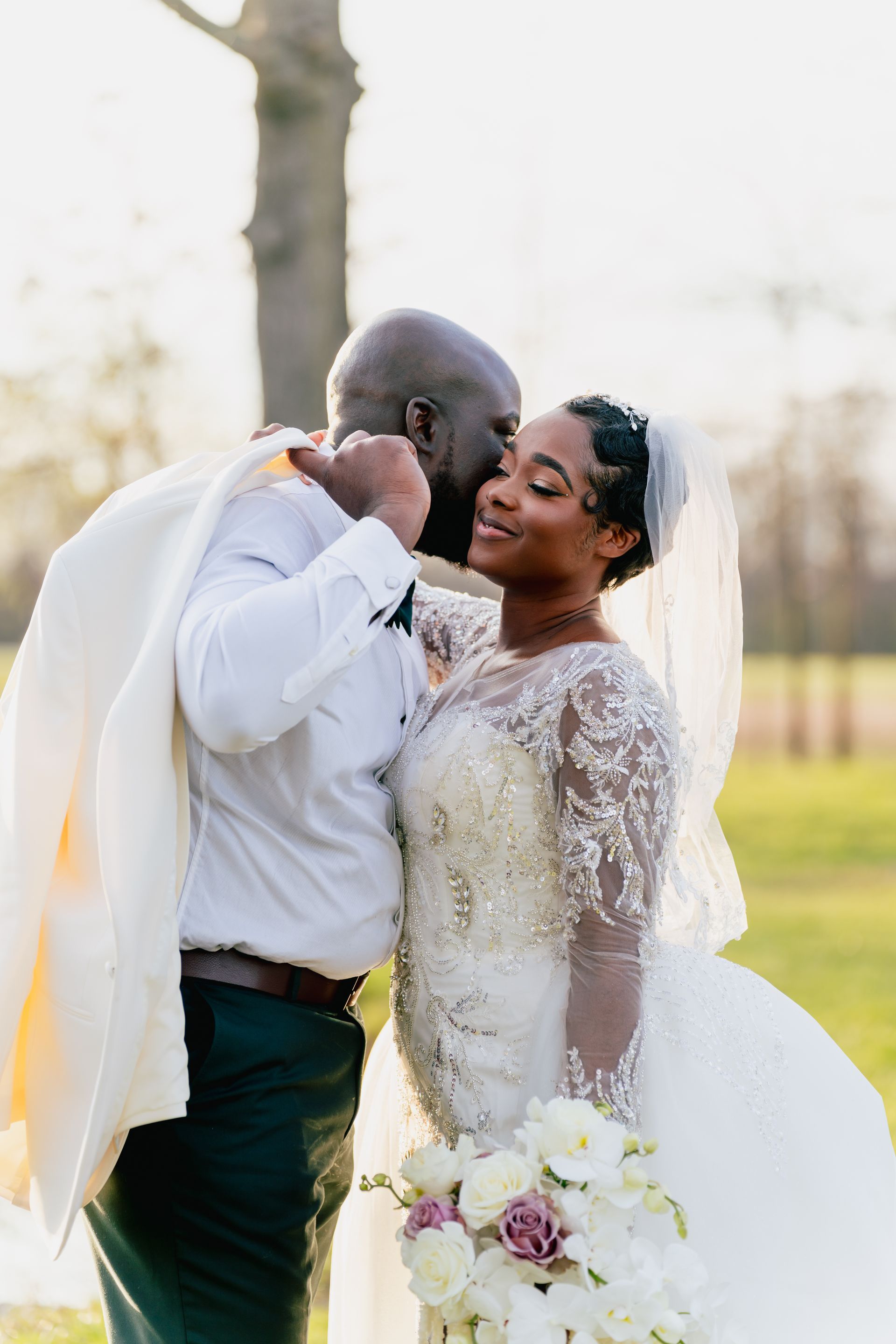 A bride and groom are kissing by a pond on their wedding day.