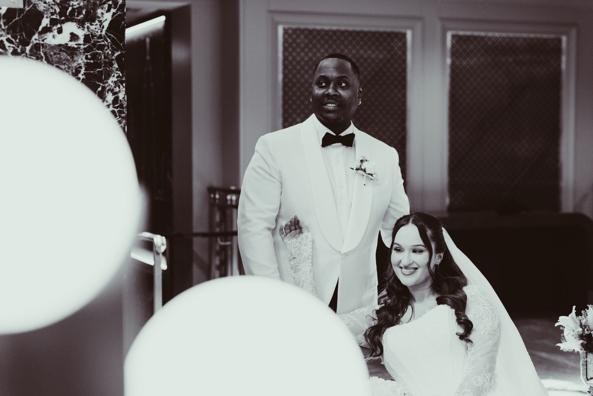 Bride and groom posing at their wedding, with large balloons in the foreground