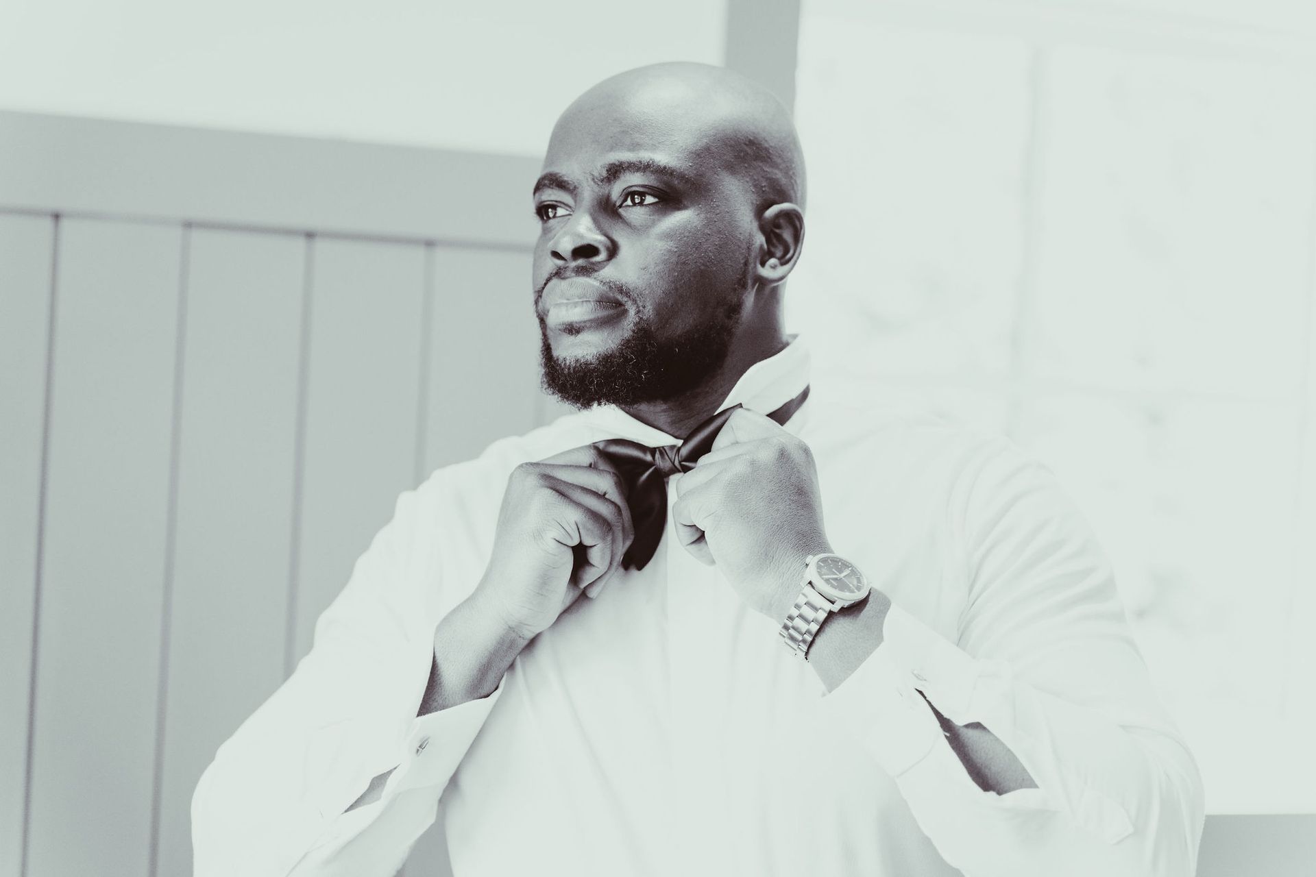 A man is adjusting his tie in a black and white photo.