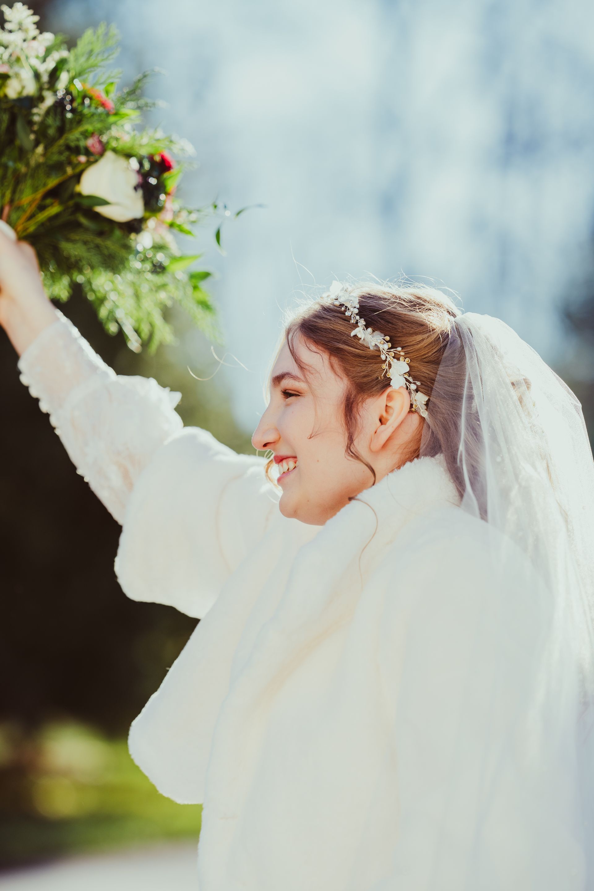 A bride in a white dress and veil is holding a bouquet of flowers.