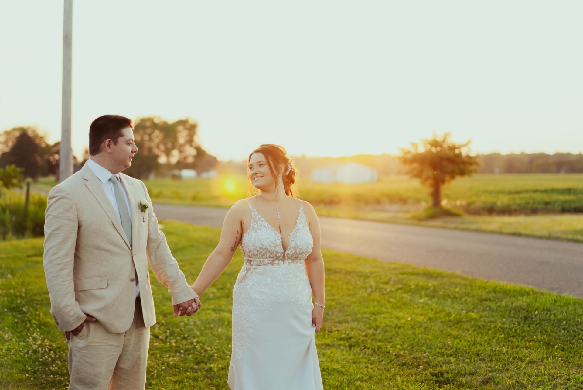 A bride and groom are holding hands while walking down a road at Four Seasons Barn Wedding & Event Venue.