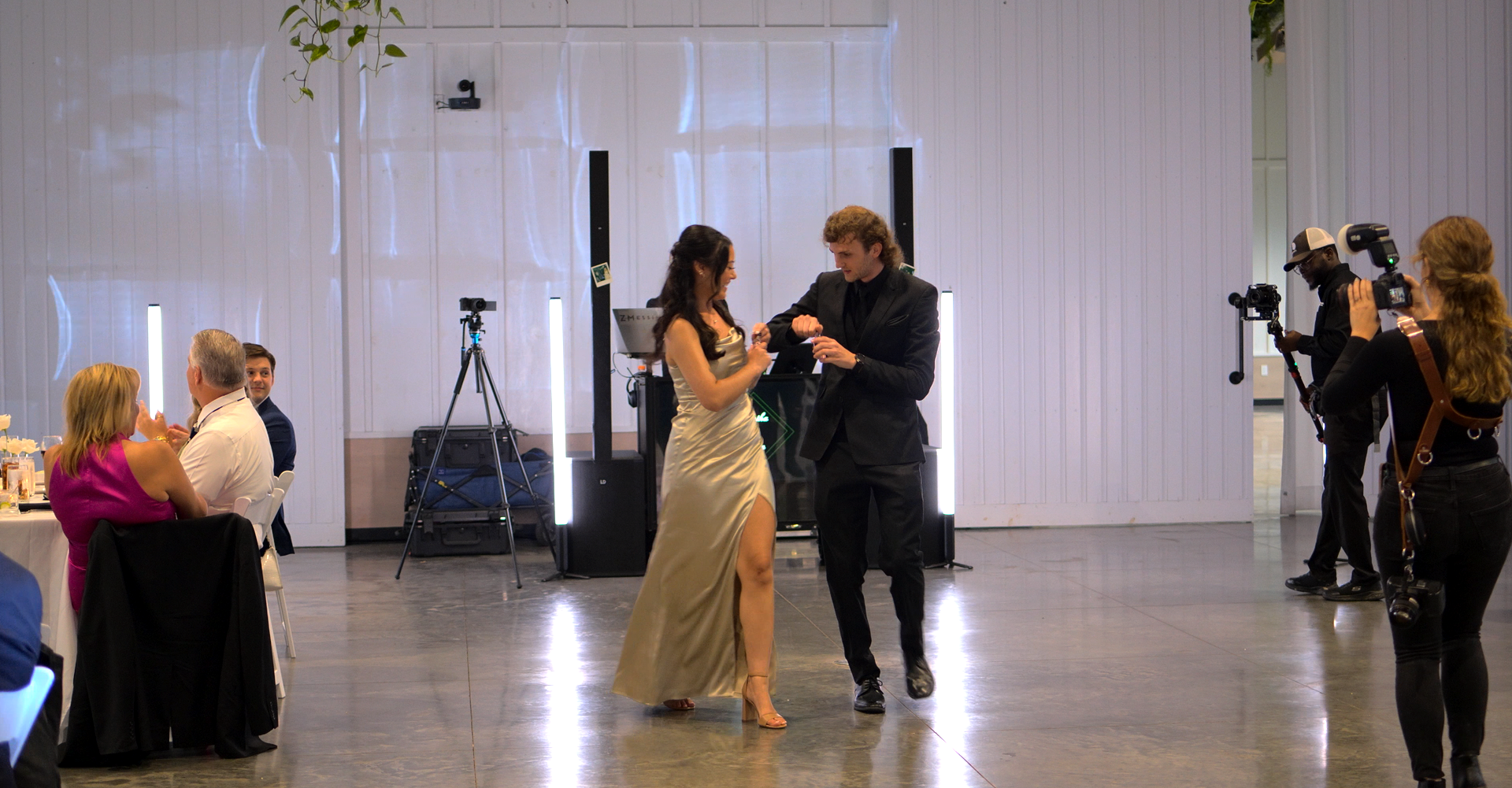 A man and a woman are dancing in a ballroom while a group of people watch at Retreat 21