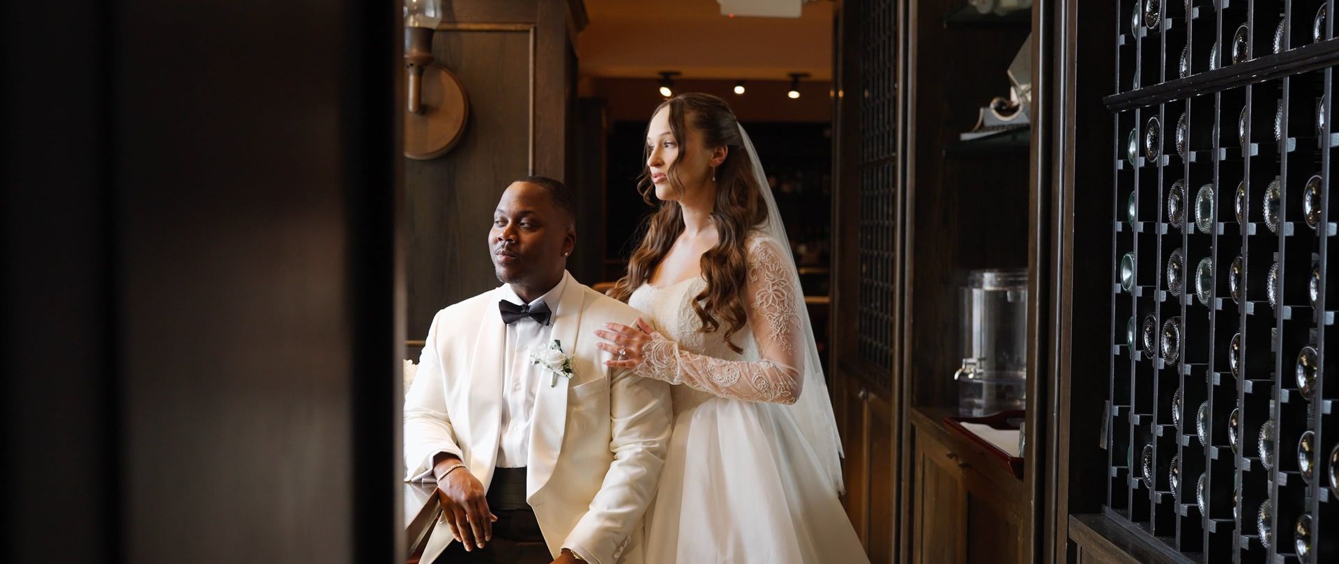 Bride and groom standing in a warm, dim hallway, holding hands and smiling