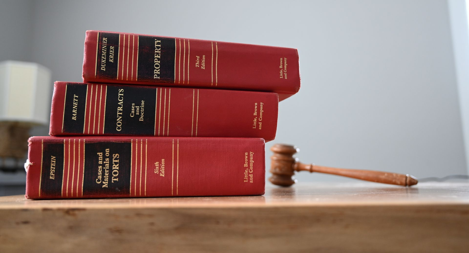 Stacked red law books beside a wooden gavel on a table