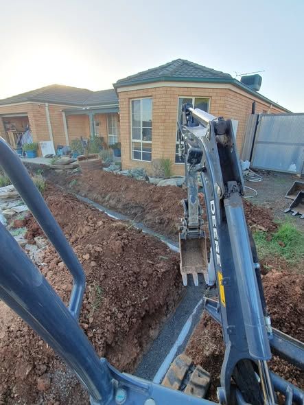 Excavator Digging a Trench Beside a Brick House in a Residential Yard — Kerney Plumbing in Caroline Spring, VIC