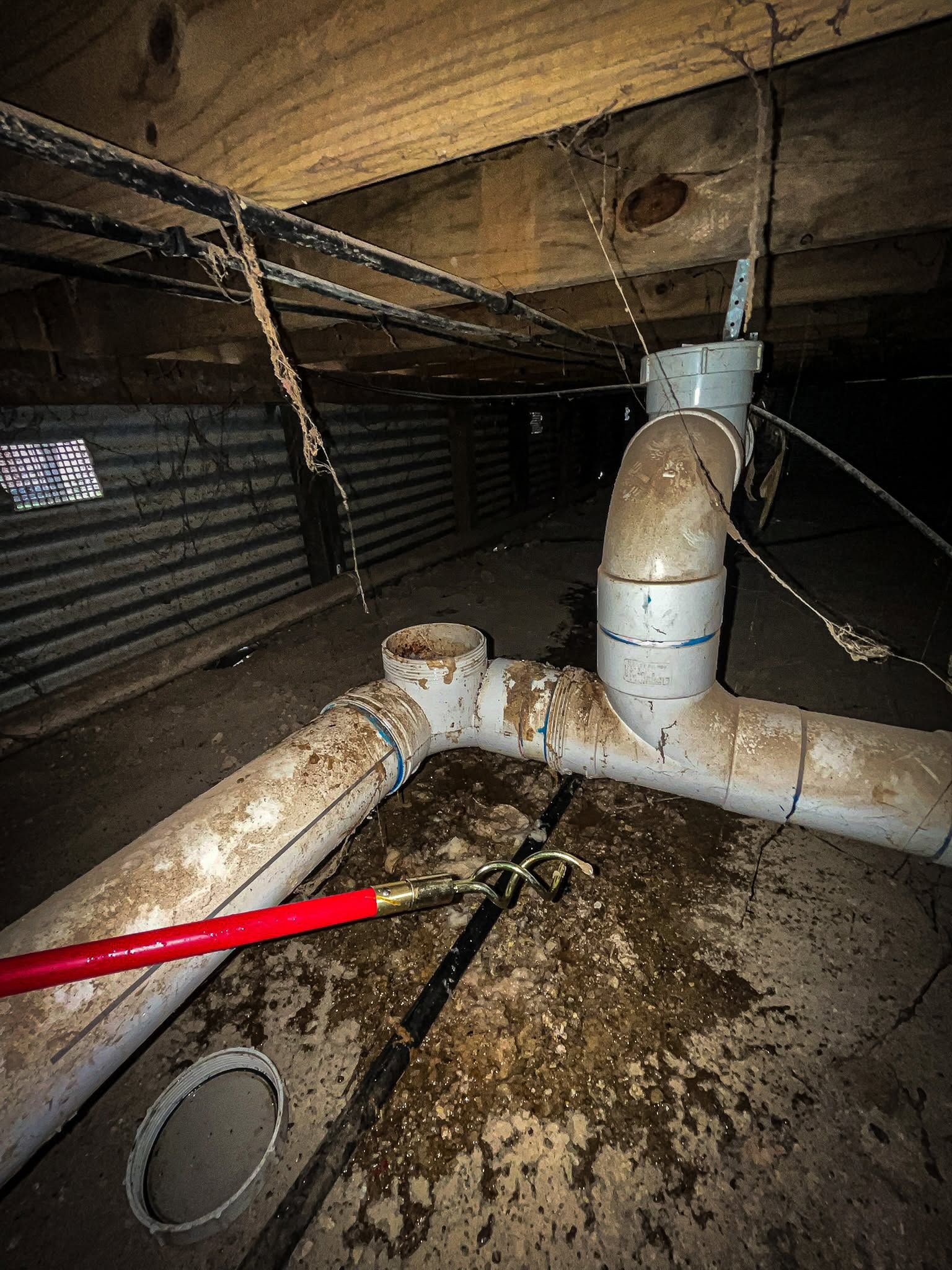 Crawlspace With a Damaged White Pvc Drain Pipe Leaking Onto Dirt and Debris Under Wooden Joists— Kerney Plumbing in Caroline Springs, VIC