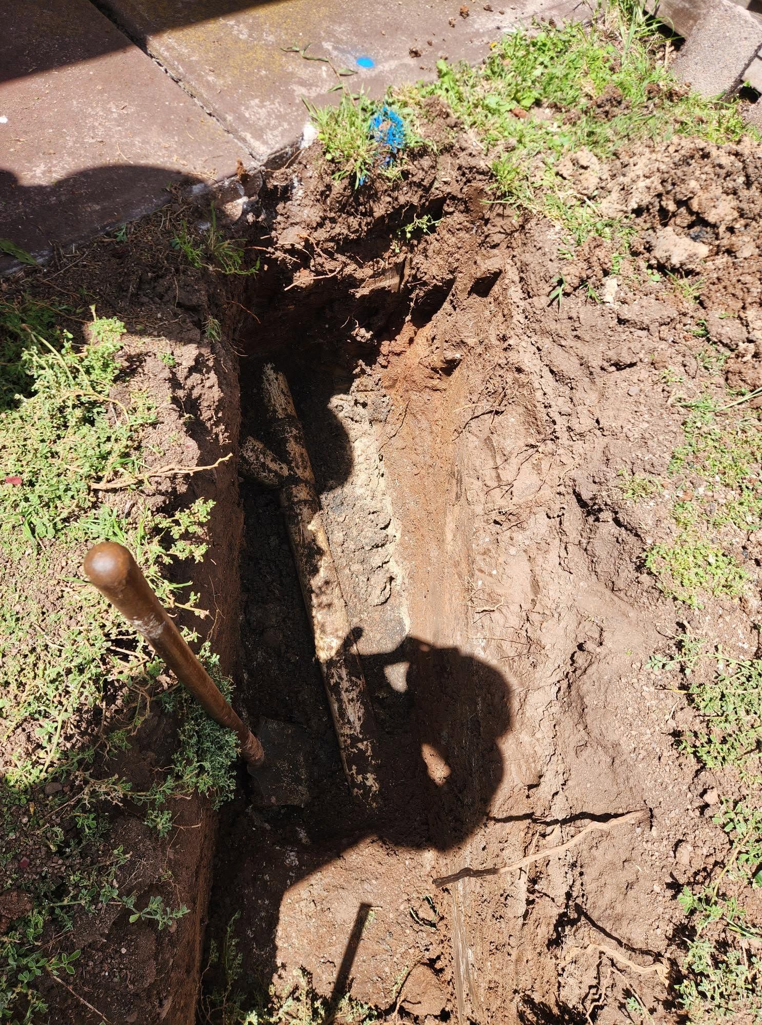 Open Trench in Dirt Beside a Yard, With a Shovel Handle Visible and Soil Piled Along the Edge — Kerney Plumbing in Bacchus Marsh, VIC