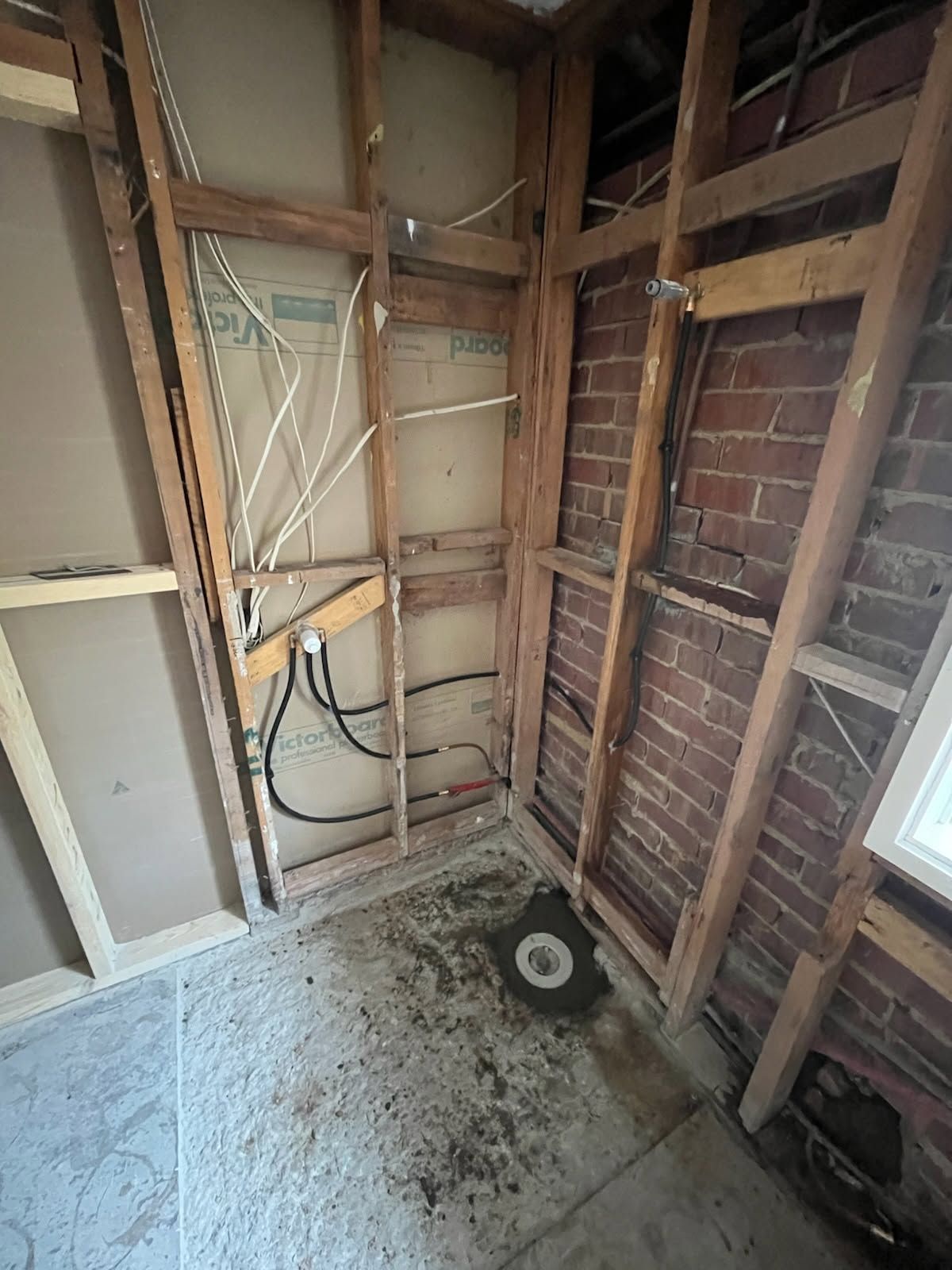 Unfinished Room With Exposed Studs, Brick Wall, Concrete Floor, and Scattered Tools Near a Window — Kerney Plumbing in Bacchus Marsh, VIC