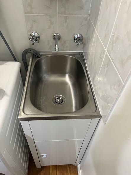 Small Stainless-steel Utility Sink With Faucet and Hose in a Tiled Bathroom Nook — Kerney Plumbing in Melton, VIC