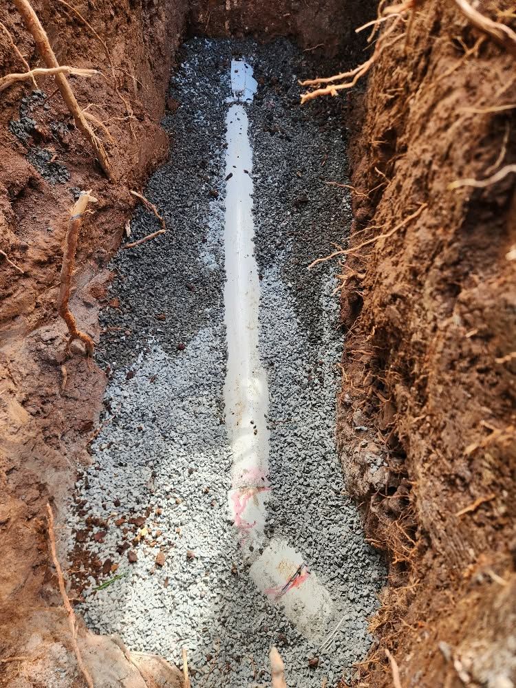 White PVC Pipe in a Narrow Trench, Surrounded by Gravel and Reddish Dirt Soil — Kerney Plumbing in Ballarat, VIC