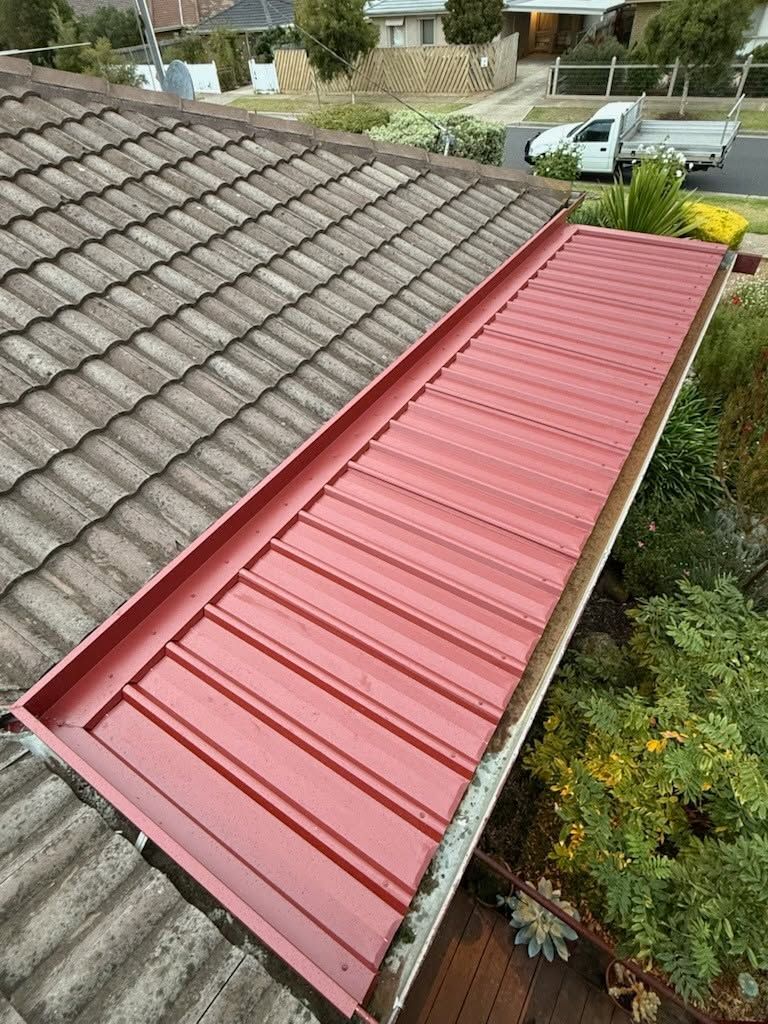 Red Metal Roof Extension Beside a Gray Tiled House Roof — Kerney Plumbing in Bacchus Marsh, VIC