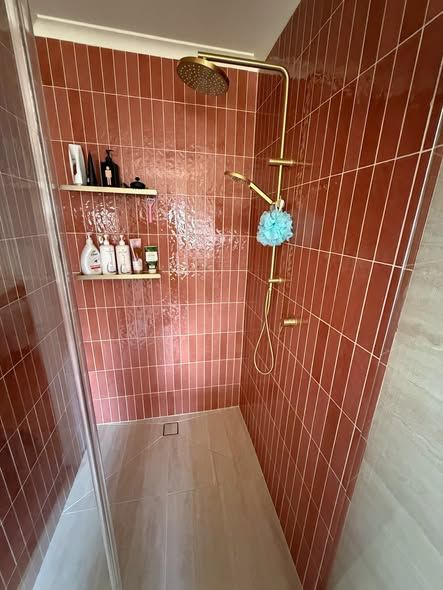Terracotta-tiled Shower Stall With a Gold Showerhead and Shelves Holding Toiletries — Kerney Plumbing in Caroline Spring, VIC