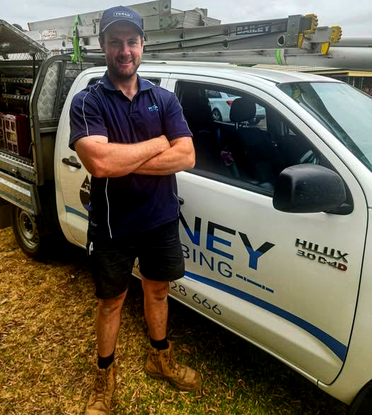 Man Standing With Arms Crossed Beside a White Utility Truck With Ladders on Top — Kerney Plumbing in Bacchus Marsh, VIC