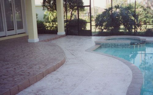 Concrete patio with pool, cream-colored concrete walkway, beige pillars, screen enclosure, and swimming pool.