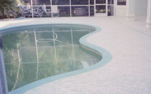 Pool with teal trim and a light-colored deck, reflecting a screened-in enclosure and surrounding architecture.
