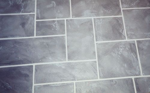 Gray tile flooring with white grout, resembling stone blocks.