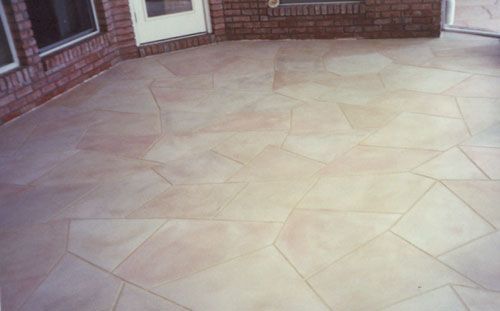 Beige patio with irregularly shaped stones against brick walls and a white door.