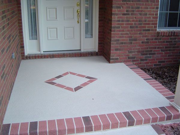Front porch with light-colored concrete floor, brick border, and a diamond-shaped brick design.