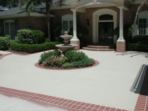 Front yard with fountain and brick trim, leading to a brick and dark door house.