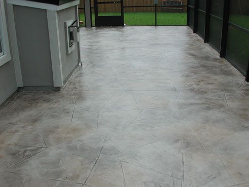 Concrete patio with a mottled gray finish and scored lines, enclosed by screening.