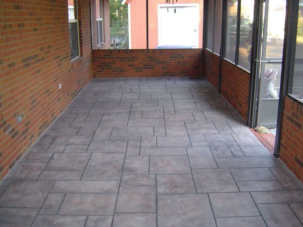 Screened-in porch with brick walls and gray concrete tile floor. Daylight streams in.