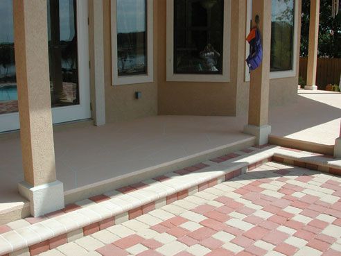 Beige patio with columns, steps, and a brick patio in a sunny setting.