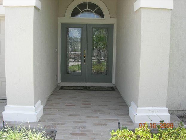 Entrance of a house with double glass doors, gray paint, and columns.