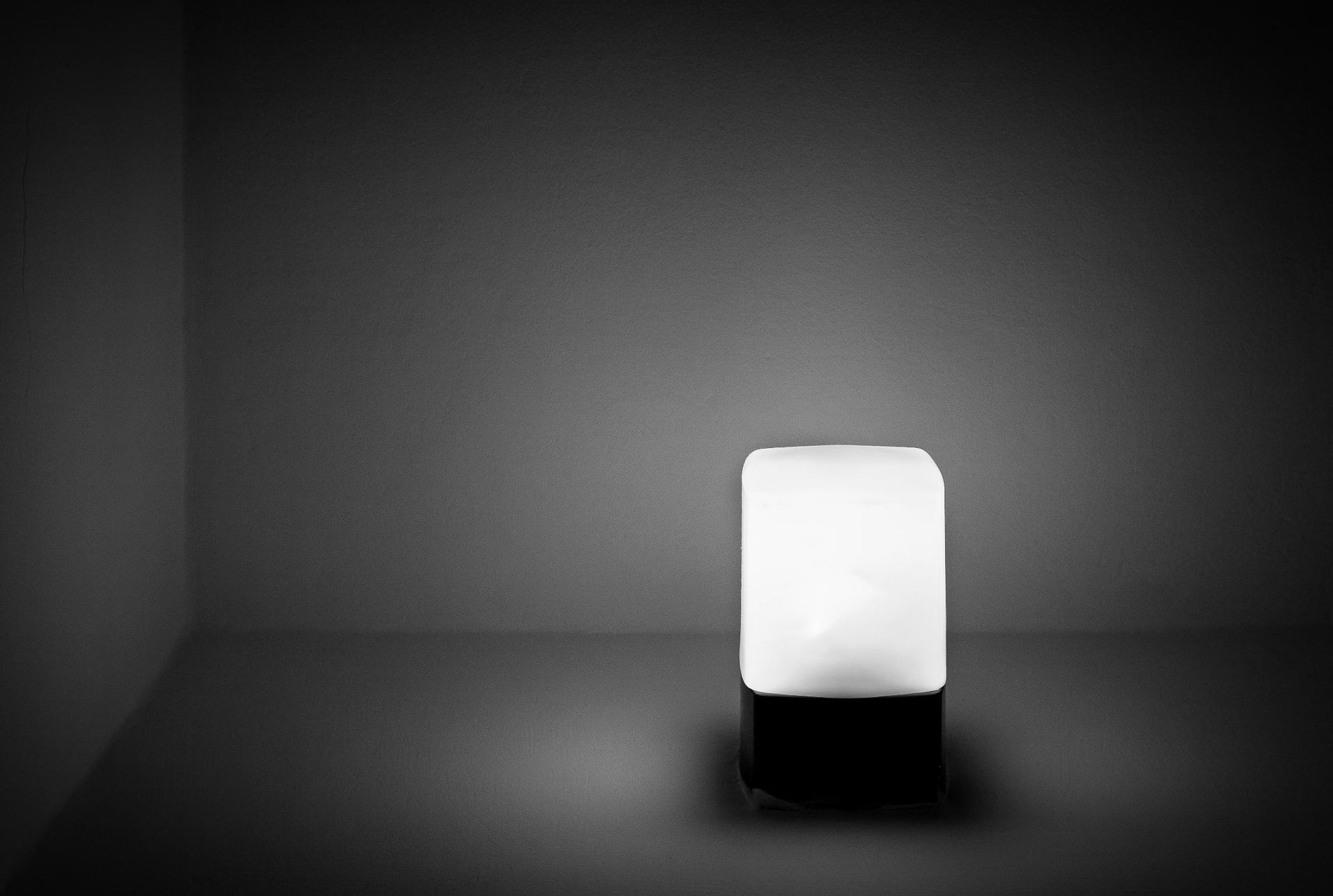 A black and white photo of a lamp in a dark room.