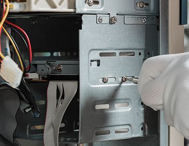 A person wearing white gloves is working on a computer.