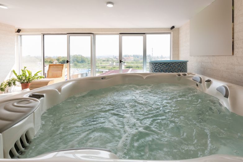 A large jacuzzi tub filled with water in a room with lots of windows.