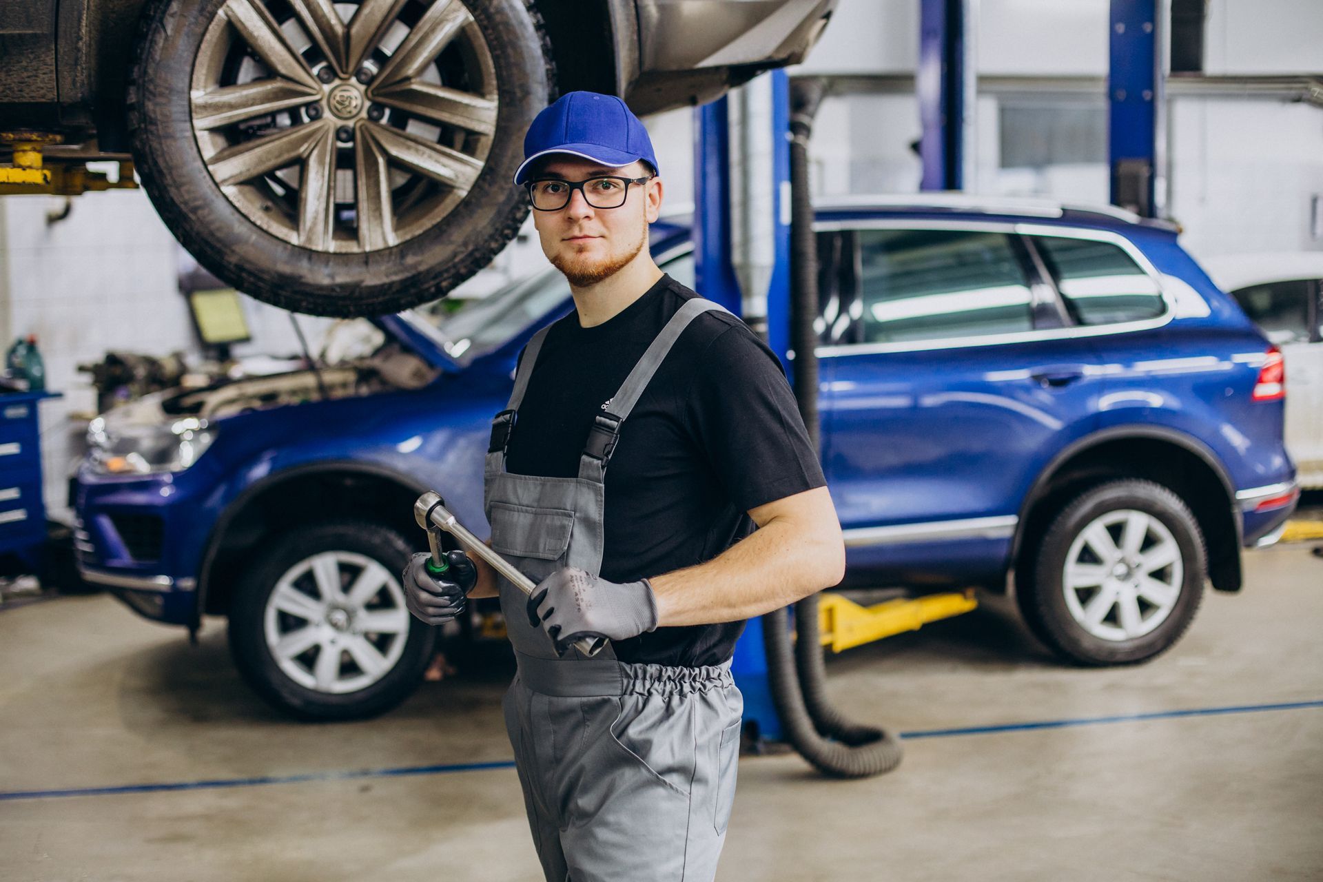 a man is standing in front of a car on a lift in a garage .