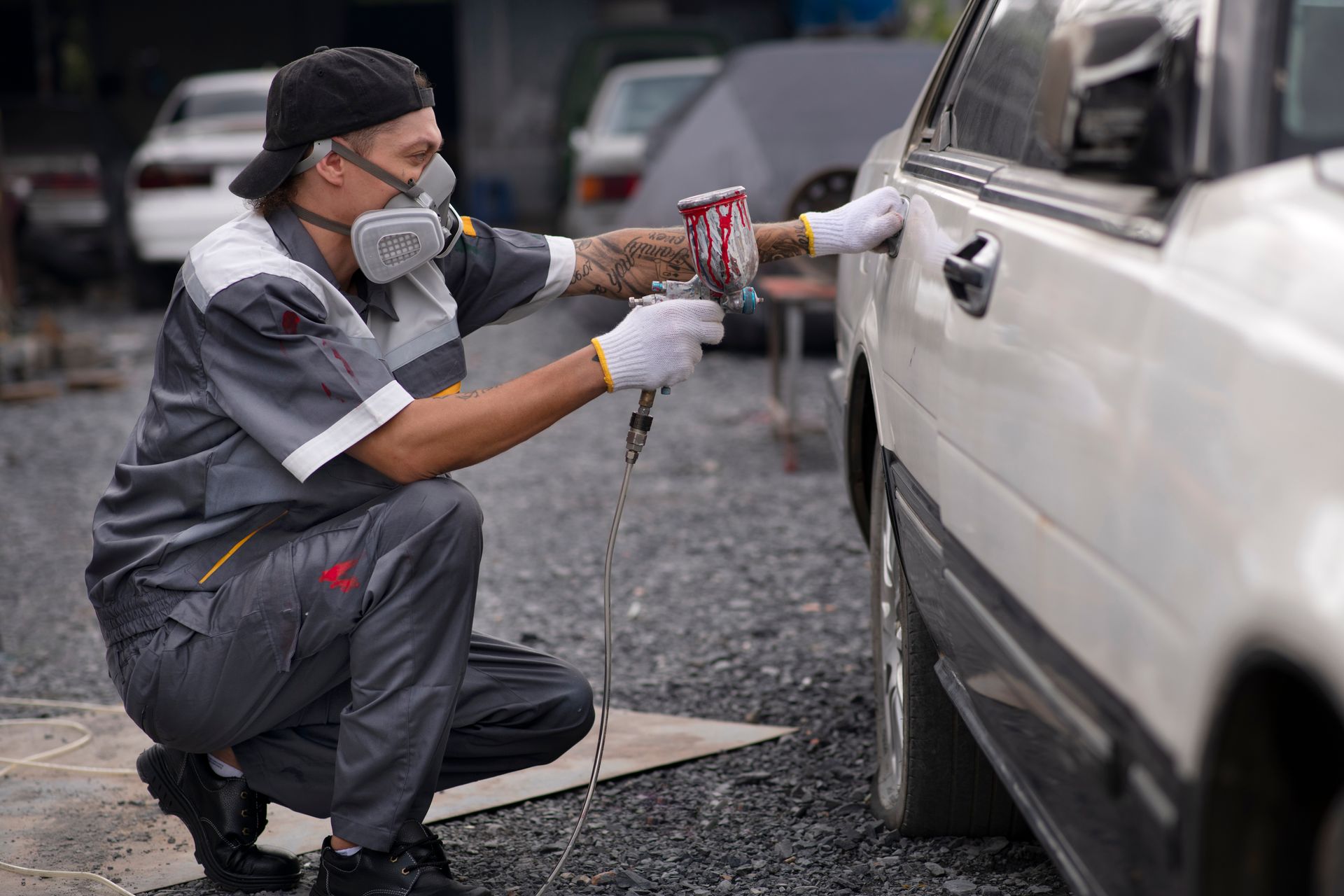 a man wearing a mask is spray painting a car .