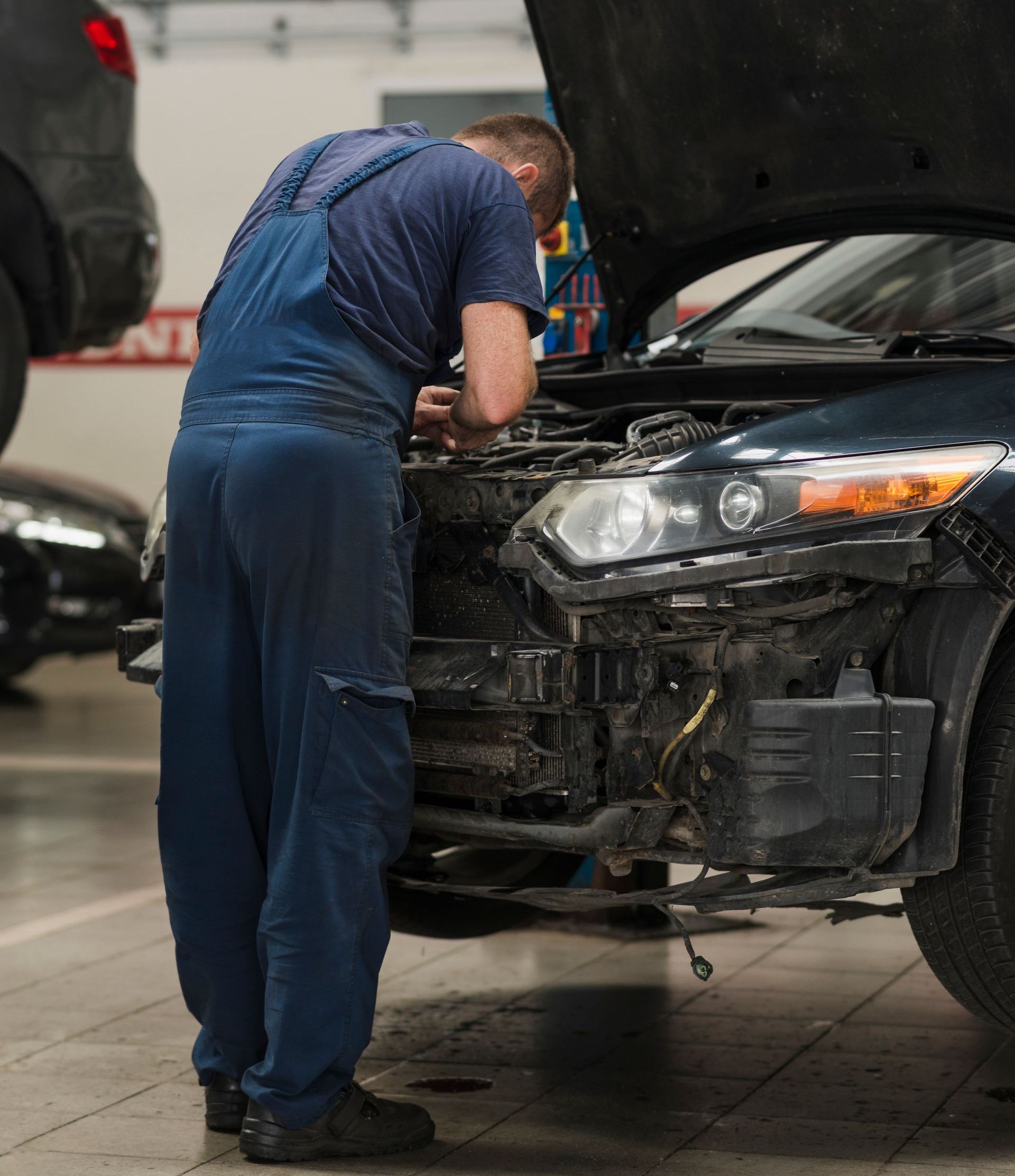a man is working on a car in a garage with the hood open .