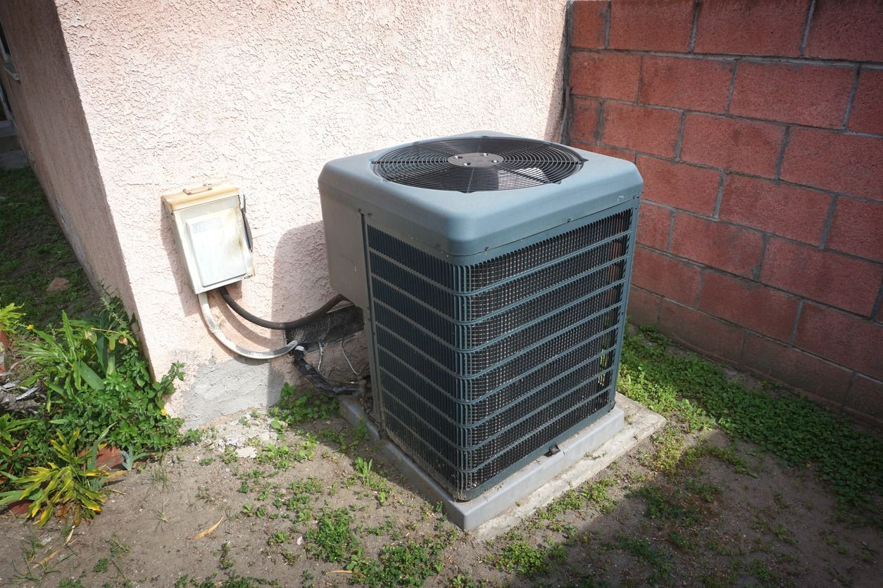 A large air conditioner is sitting outside of a building.