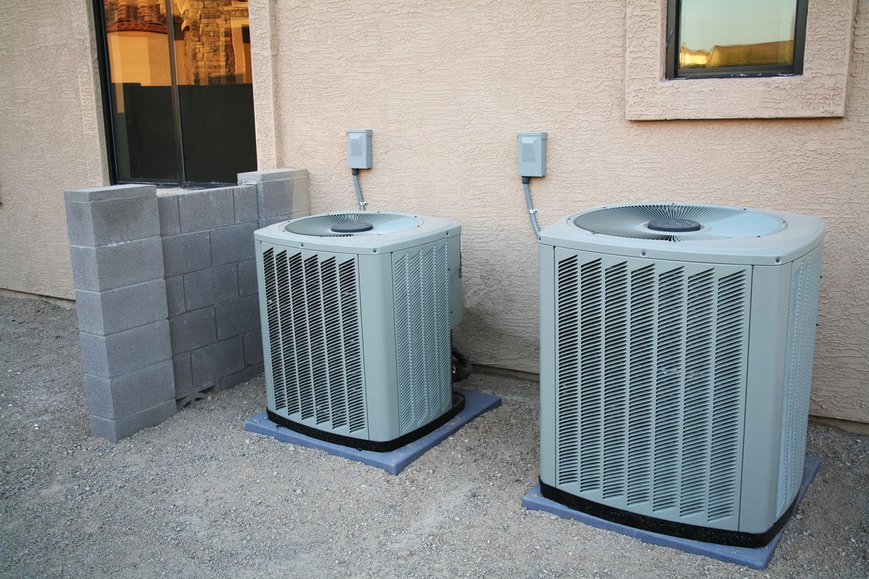 Two air conditioners are sitting outside of a building.