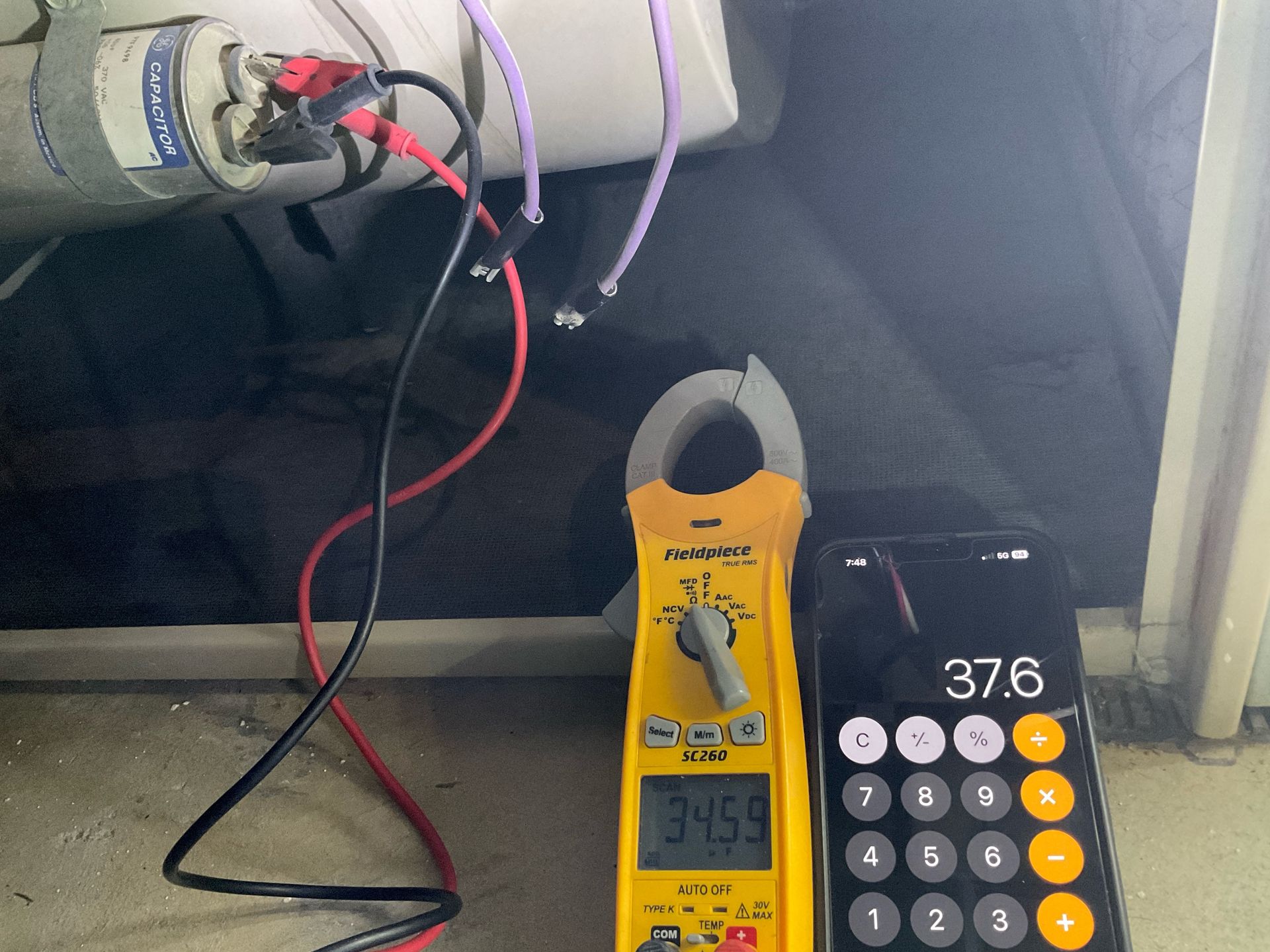 A calculator next to a clamp meter that reads 3451