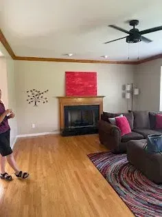 Living room with fireplace, brown sofa, red abstract art, and hardwood floors.