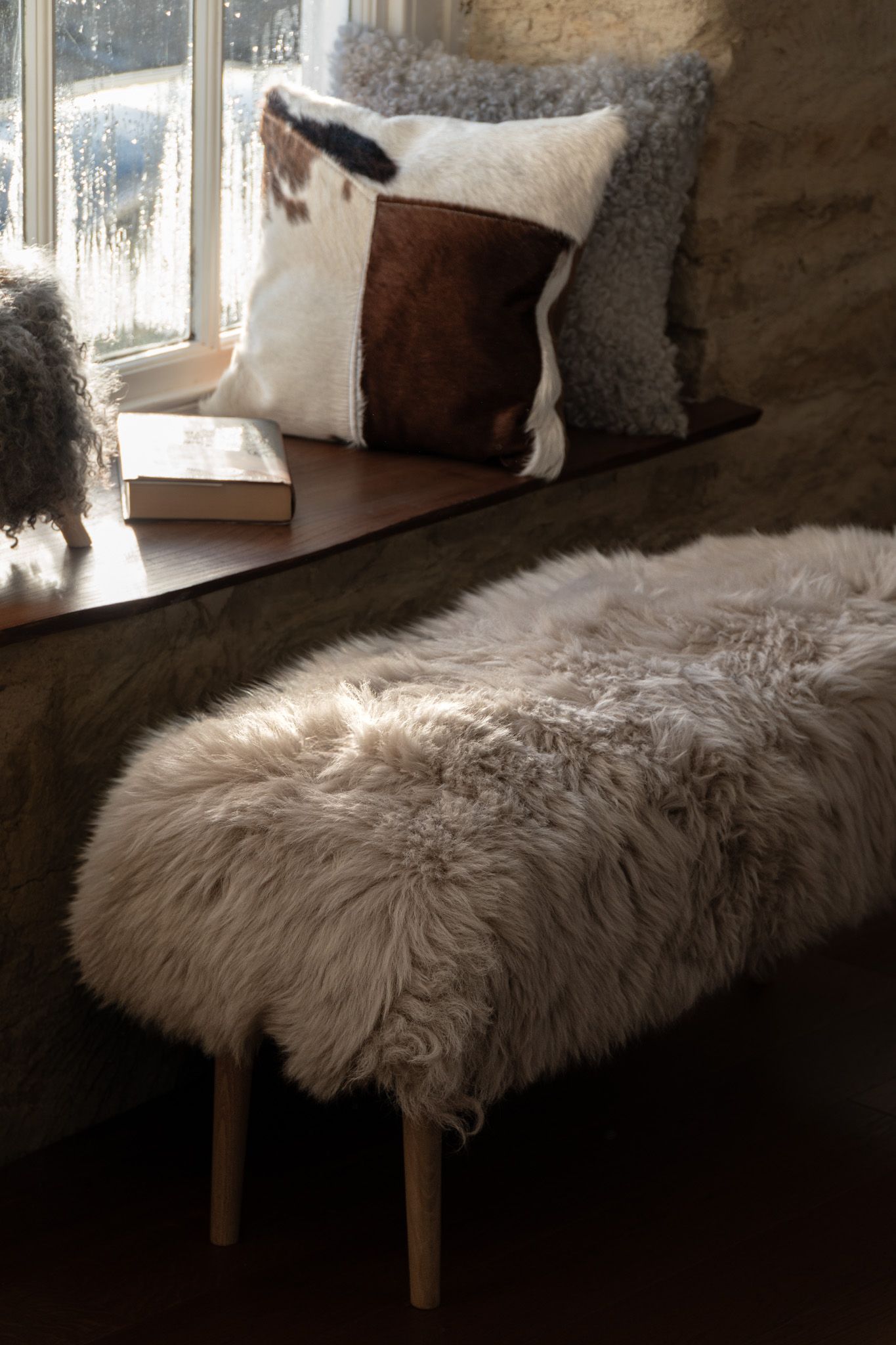 Brown and cream sheepskin cushion in a rustic Cotswold interior