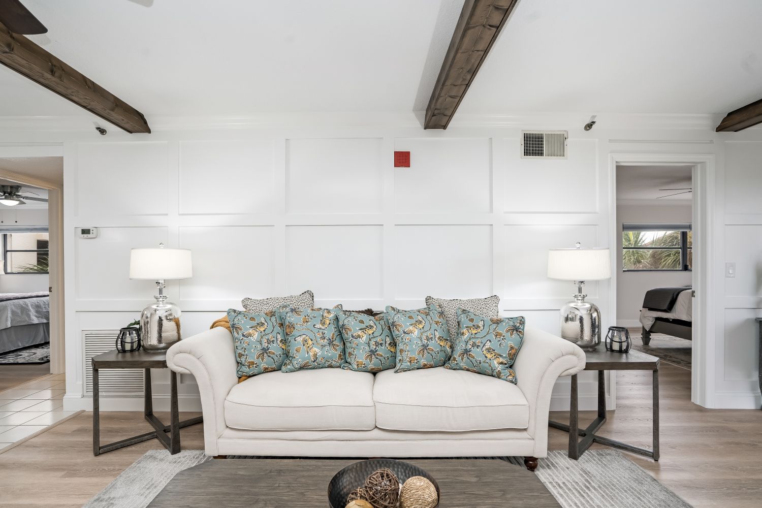 A living room with a white couch and blue pillows.