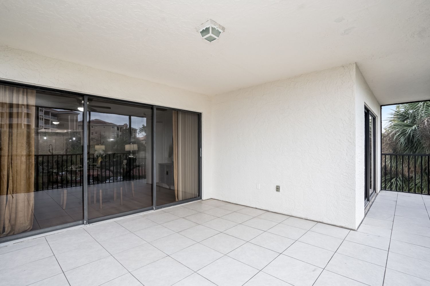 An empty patio with sliding glass doors and a tiled floor
