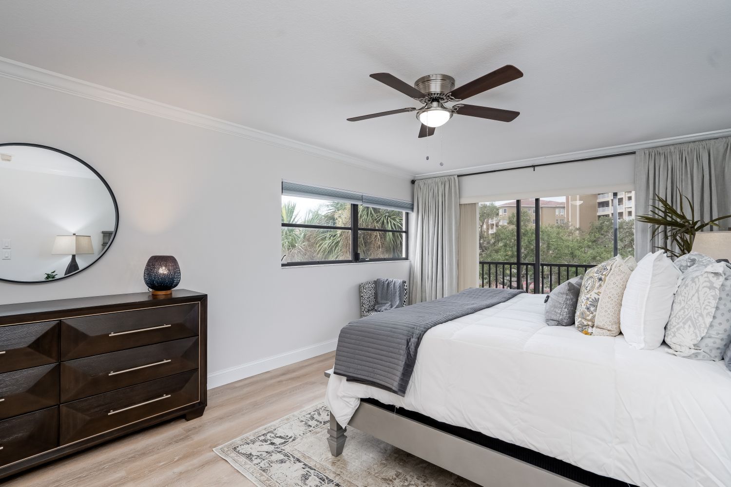 A bedroom with a bed , dresser , mirror and ceiling fan.