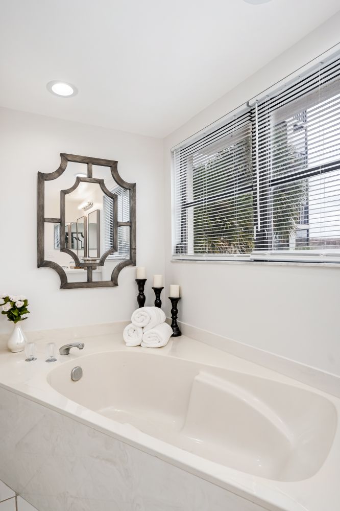 A bathroom with a bathtub , mirror , candles and towels.