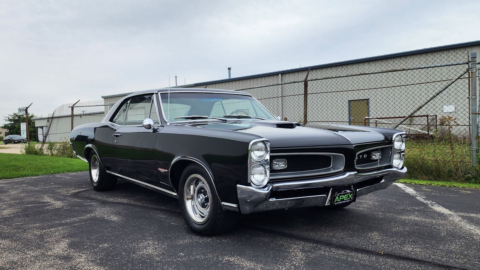A Pontiac GTO car is parked in a parking lot in front of a building.