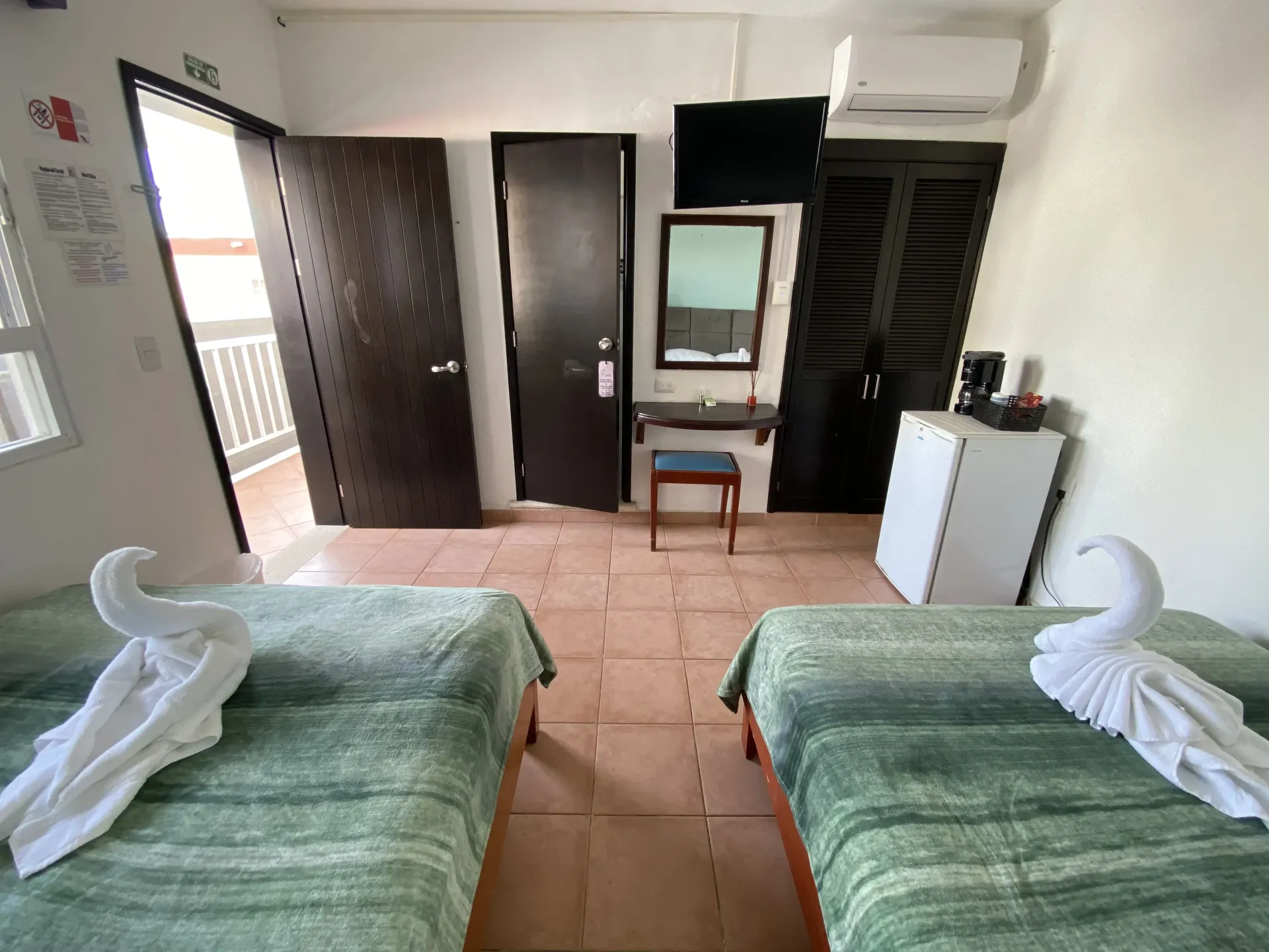 Dos camas en habitación ordenada con puerta al balcón, escritorio, t.v., espejo, minibar y aire acondicionado.